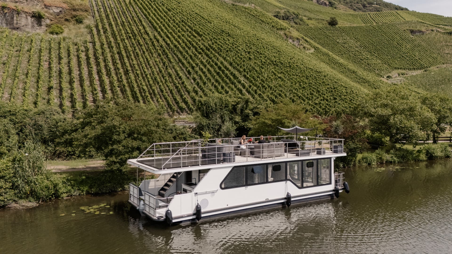 Die SOLEJO auf der Mosel vor Weinbergen, Luftaufnahme mit Gästen auf dem Sonnendeck